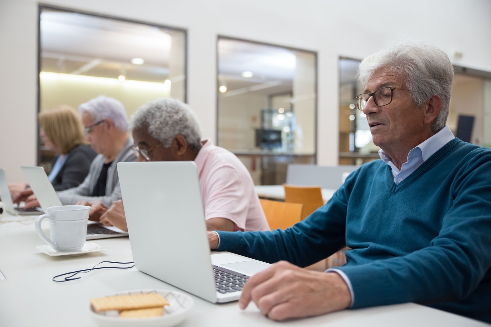 Adult learners of all ages practicing on laptops in a community class