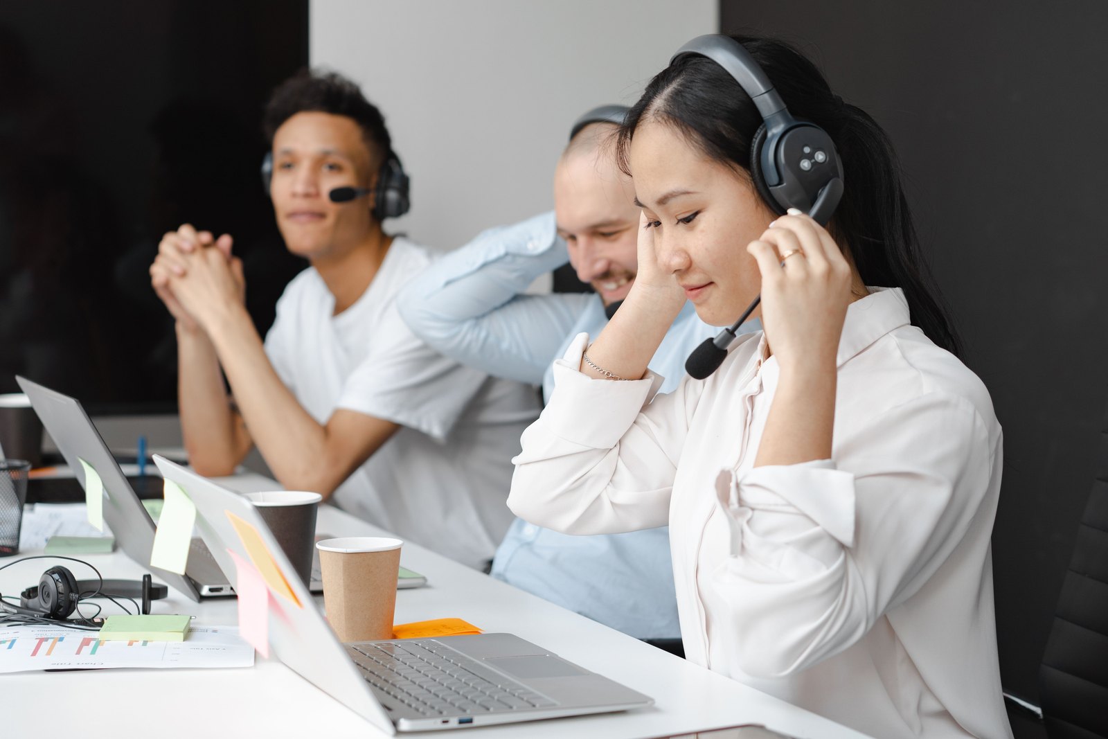 Consultation team ready to take your call Support team member adjusting her headset at a busy help desk