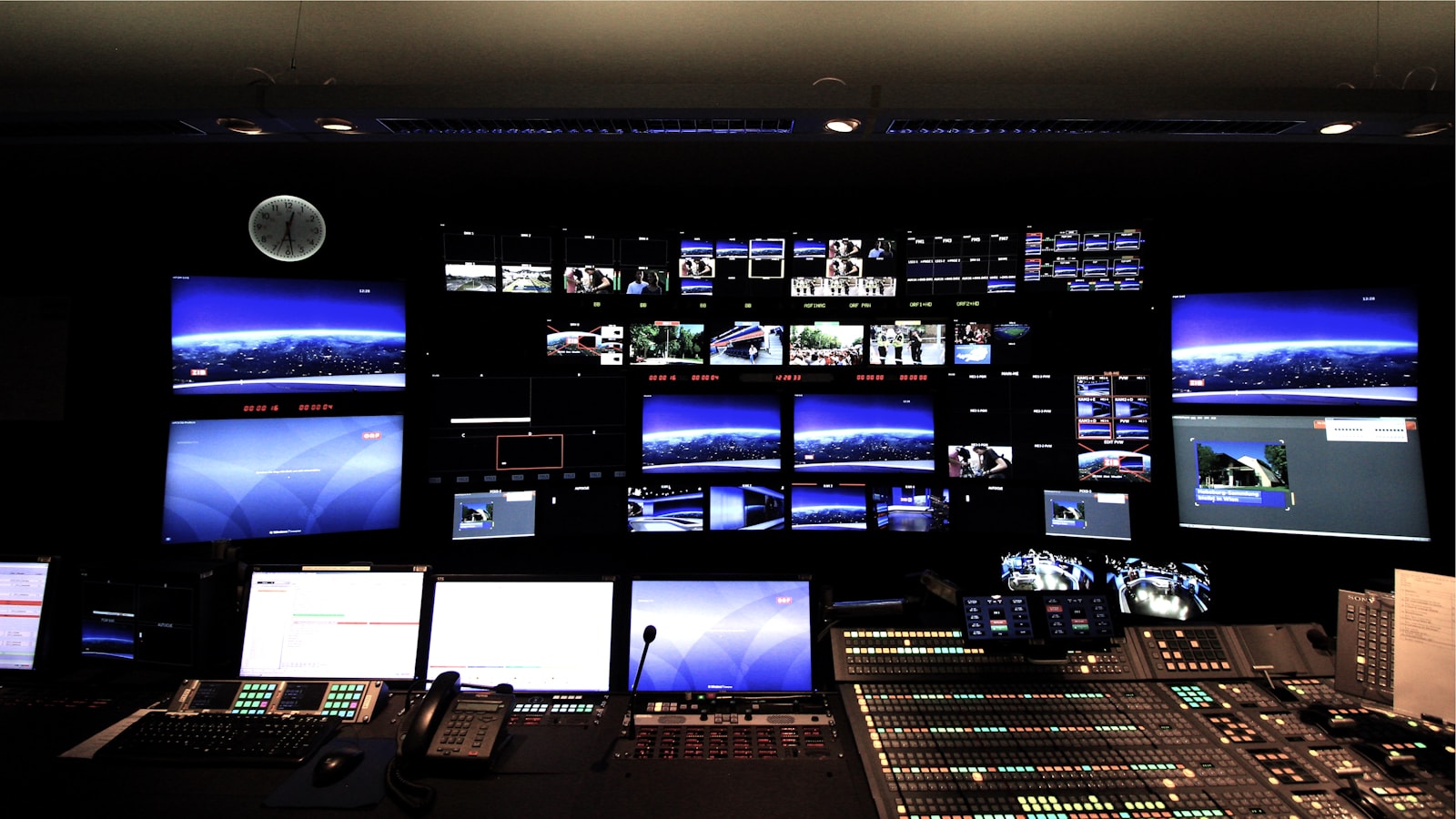 A darkened command center with a wall of live operational displays